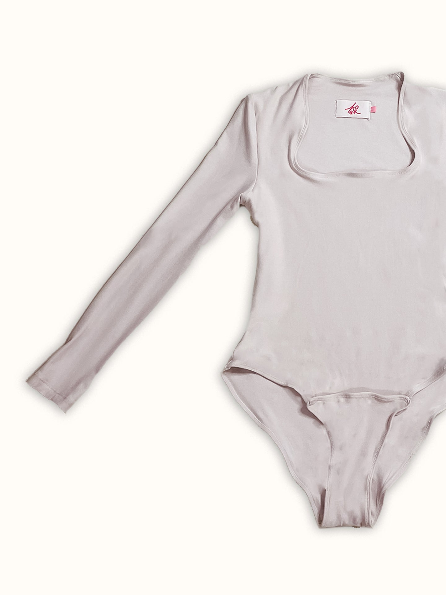 A long-sleeve jersey bodysuit made from deadstock fabric, featuring a square neckline and front snaps. A made-to-order piece